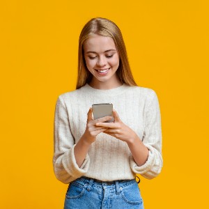 beautiful-girl-messaging-on-smartphone-over-orange-2023-11-27-05-34-21-utc