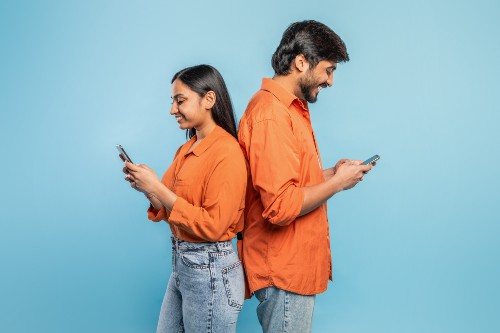 young-couple-engrossed-in-smartphones-on-blue-back-2024-04-10-22-52-26-utc